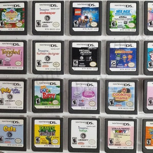 May include: A collection of 18 Nintendo DS game cartridges, including titles like "Tangled", "Zookeeper", "Dora Saves the Mermaids", "Plants vs Zombies", and "Hello Kitty Party".