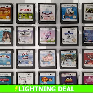 May include: A collection of 18 Nintendo DS game cartridges in clear plastic cases. The cartridges are arranged in a grid of three rows and six columns. The games include titles such as "Card Games", "Yamaha Supercross", "Pony", "Brain Boost", "Shrek: Ogres & Drakons", "My Horse & Me", "Disney Wizards", "My Scene: Sweet Style", "The Smurfs", "Brain Age 2", "Pet Resort", "Cars", "Dragon", "Imagine: Movie Star", "Phineas and Ferb: Ride Again", "CN Racing", "Barbie: Princess & Popstar", and "Cooking Mama".