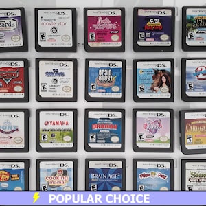 May include: A collection of 18 Nintendo DS game cartridges displayed in a clear plastic case. The cartridges are arranged in four rows of four, with each cartridge featuring a different game title and cover art. Some of the games include "Cars", "Brain Age", "Shrek", "Cooking Mama", "Imagine Movie Star", "Yamaha Supercross", "Brain Boost", and "Pet Resort".