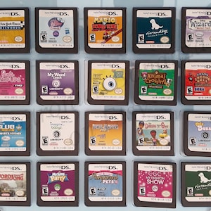 Puede incluir: Una colección de cartuchos de juegos de Nintendo DS, con títulos como "The New York Times Crosswords", "Mario & Donkey Kong" y "Animal Crossing". Los juegos están en carcasas negras con ilustraciones coloridas.