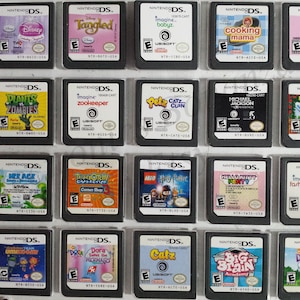 May include: A collection of Nintendo DS game cartridges, featuring titles like "Disney Princess," "Tangled," "Plants vs. Zombies," and "Lego Harry Potter." The cartridges are in clear protective cases.