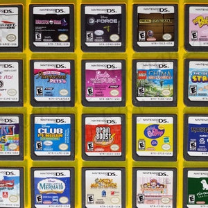 Puede incluir: Una colección de 16 cartuchos de juego de Nintendo DS que se muestran en una caja de plástico amarilla. Los cartuchos están dispuestos en cuatro filas de cuatro. Los cartuchos son de diferentes colores y tienen diferentes títulos, incluyendo "Mario Kart DS", "Monster High", "G-Force", "Deal or No Deal", "Imagine Movie Star", "Pampered Pets", "Barbie Groom & Glam Pups", "LEGO Chima", "Tetris DS", "Club Penguin", "Brain Boost", "Just Dance:  Kids", "Rock Band 3", "Backyard Sports", "The Little Mermaid", "Crazy Machines", "Cooking Mama 2" y "Nintendogs".