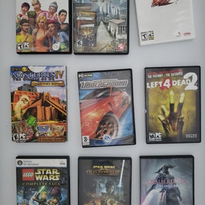 Może przedstawiać: Kolekcja dziewięciu pudełek z grami na PC, w tym The Sims 4, Civilization V, Guild Wars, Jewel Mysteries IV, Need for Speed Underground, Left 4 Dead 2, Lego Star Wars: The Complete Saga, Star Wars: The Old Republic i A Realm Reborn.
