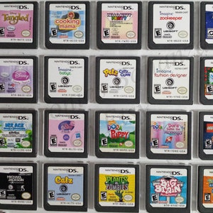 May include: A collection of 18 Nintendo DS game cartridges, displayed in a grid. The cartridges are various colors and feature popular characters and titles, including Tangled, Cooking Mama, Hello Kitty, Zookeeper, Imagine Babyz, Petz Catz, Dora the Explorer, and more.