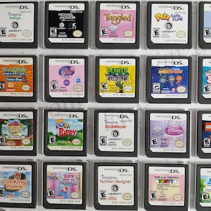 May include: A collection of 18 Nintendo DS game cartridges, displayed in a clear plastic case. The cartridges feature a variety of popular games, including "Imagine: Babyz", "Michael Jackson: The Experience", "Tangled", "Petz: Catz Clan", "Catz", "Turok: Evolution", "Friends", "Plants vs. Zombies", "Team Umizoomi", "Big Brain Academy", "Dora the Explorer:  Parading  Marimba", "Dora the Explorer: Puppy", "Imagine: Zookeeper", "Disney Princess:  Enchanted Journey", "LEGO Harry Potter", "Dora the Explorer:  Saves the Mermaids", "Imagine: Fashion Designer", "Hello Kitty: Party", "Ice Age:  Dawn of the Dinosaurs", and "Max & The Magic Marker".