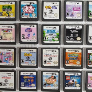 May include: A collection of 18 Nintendo DS game cartridges, displayed in a clear plastic case. The cartridges feature a variety of popular games, including Plants vs. Zombies, Big Brain Academy, Petz Catz Clan, Dora the Explorer, Hello Kitty Party, and more.