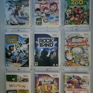 May include: A collection of nine video game cases for the Nintendo Wii console. The cases are arranged in three rows of three. The games include "We Ski", "Cooking Mama World Kitchen", "World of Zoo", "Star Wars: Clone Wars - Lightsaber Duels", "Rock Band", "My Sims Kingdom", "Wii Play", "My Sims Party", and "Namco Museum Remix".