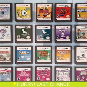Pode incluir: Uma coleção de 18 cartuchos de jogo Nintendo DS exibidos em uma caixa de plástico transparente. Os cartuchos estão dispostos em três filas de seis. Os cartuchos são de diferentes cores e têm diferentes títulos de jogos impressos neles. Os títulos incluem "Bunnyz", "Mario", "Club Penguin", "Animal Crossing", "Jewel Master", "Imagine Babyz", "WordJong", "My Word Coach", "Dakine to Go", "Pampered Pets", "Barbie: Dashing Puppies", "EGG My Fashion Show", "Disney Wizards" e "MySims Party".