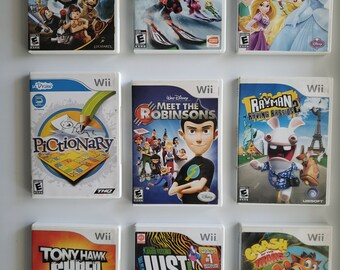 May include: A collection of nine video game cases for the Nintendo Wii console. The cases are arranged in three rows of three. The games include Lego Star Wars: The Complete Saga, We Ski, Disney Princess: My Fairytale Adventure, Pictionary, Meet the Robinsons, Rayman Raving Rabbids, Tony Hawk Shred, Just Dance 4, and Crash of the Titans.