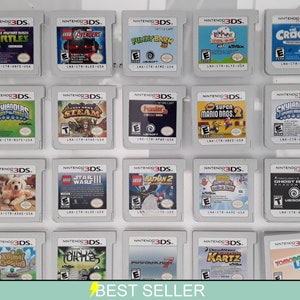 Könnte beinhalten: Eine Sammlung von 16 Nintendo 3DS-Spielkassetten, die in einem Regal ausgestellt sind. Die Kassetten sind in vier Reihen zu je vier angeordnet. Die Kassetten sind alle in verschiedenen Farben und haben unterschiedliche Spieltitel. Einige der Titel sind "Teenage Mutant Ninja Turtles", "LEGO Avengers", "Skylanders", "LEGO Star Wars III", "Animal Crossing" und "LEGO Batman 2".