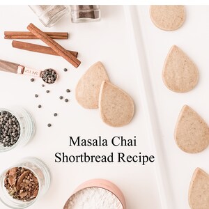 May include: A white surface with a bowl of white powder, two jars of spices, and a row of six light brown teardrop-shaped cookies. The text "Masala Chai Shortbread Recipe" is written in black on the white surface.