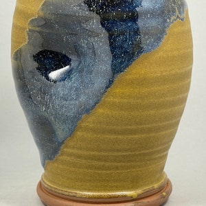 May include: A ceramic vase with a blue and yellow glaze. The vase has a rounded body and a wide base.