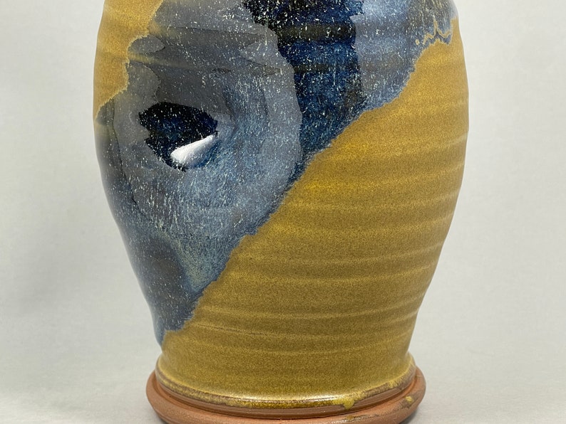 May include: A ceramic vase with a blue and yellow glaze. The vase has a rounded body and a wide base.