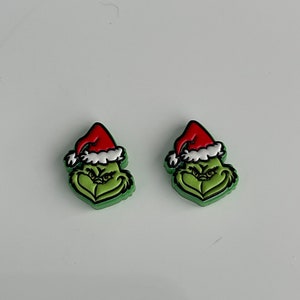 May include: Two green Grinch Christmas shoe charms with red Santa hats.