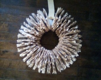 May include: A wreath made from the pages of a book, with a white ribbon attached to the top.