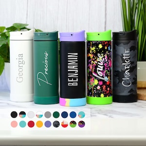 May include: Five stainless steel travel mugs with different coloured lids and designs. The mugs are white, green, black, black with colourful paint splatters, and grey with a camouflage pattern. Each mug has a name on it: Georgia, Precious, Benjamin, Louise, and Charlotte.
