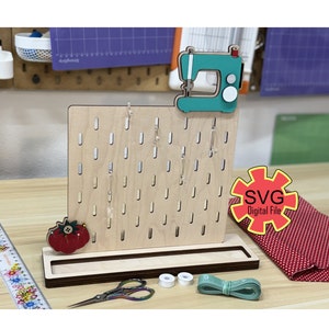 May include: A wooden sewing needle organizer with a sewing machine design on top. The organizer has a slot for storing needles and a small tray for storing other sewing supplies. The organizer is made of wood and has a natural finish. The organizer is a digital file, SVG format.