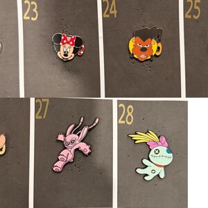 May include: A collection of Disney character enamel pins, including Tod from Fox and the Hound, Minnie Mouse, a character from Beauty and the Beast, Pinocchio, Bambi, Angel, and a Stitch variant. Each pin is colorful and detailed, with a glossy finish.