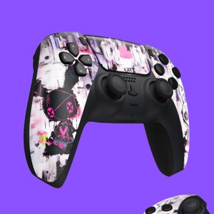 May include: Two black and white patterned video game controllers with pink accents. The controllers have a textured surface and a unique design.