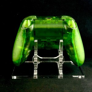 May include: A clear green video game controller on a clear acrylic stand. The controller is translucent and shows the internal components.