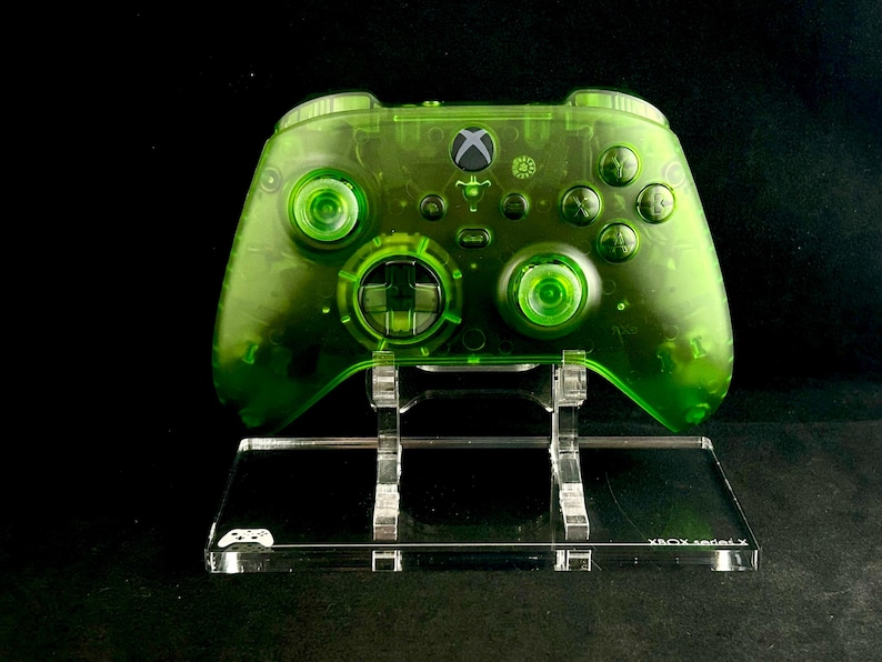 May include: A clear green Xbox Series X controller on a clear acrylic stand. The stand has the text "XBOX Series X" printed on the front.
