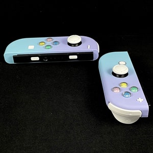 May include: Two purple and white Nintendo Switch Joy-Con controllers with white buttons and a black faceplate.