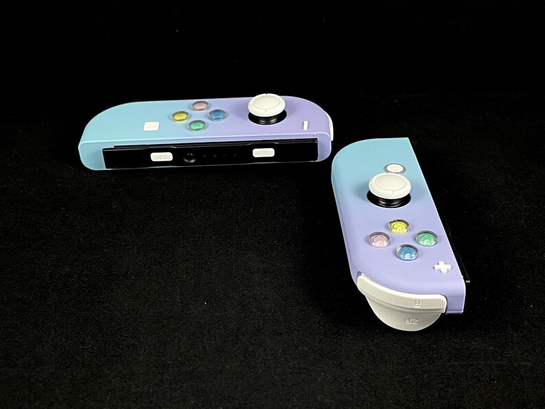 May include: Two purple and white Nintendo Switch Joy-Con controllers with white buttons and a black faceplate.