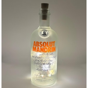May include: A clear glass bottle with an orange label that reads "ABSOLUT MANDRIN". The label also includes the text "A superb vodka with a taste of mandarin flavour and zest. It's an Absolut classic. Crafted in the village of Absolut since 1879. Imported. 700 ml."