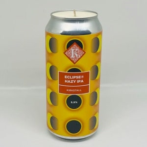 May include: A yellow and black can candle with a graphic of a repeating pattern of eclipses. The can has the text "ECLIPSE® HAZY IPA" and "KIRKSTALL" printed on it. The candle is 5.5% ABV.