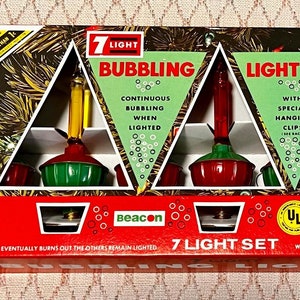 May include: A box of 7 light set Christmas lights with a red and green design. The box says "7 Light Bubbling Light Set" and "Beacon". The lights are red and green with a yellow cord. The lights are designed to bubble when lit.