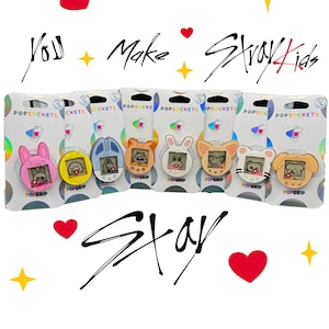 Peut inclure: Plusieurs PopSockets avec des motifs d'animaux, dont un lapin et un chien. Chaque PopSocket est fixé à une carte blanche avec les mots "POPSOCKETS" et "POPGRIP". L'image contient également le texte "You Make Stray Kids Stay".