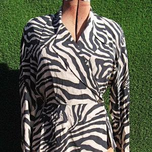 May include: A long-sleeved, black and white zebra print blouse with a wrap style front and a button closure.