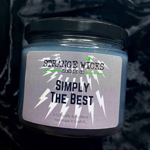 May include: A black glass candle jar with a silver label that reads "STRANGE WICKS CANDLE CO" and "SIMPLY THE BEST". The label also includes the text "8 OZ Paraffin & Soy Blend Handmade in South FL".