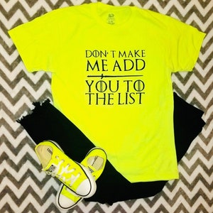 May include: A neon yellow t-shirt with black text that reads "Don't make me add you to the list". The text is in a font similar to the Game of Thrones logo. The shirt is paired with black jeans and yellow Converse sneakers.