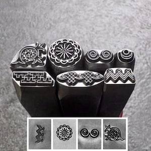 Puede incluir: Un conjunto de sellos metálicos con diversos diseños decorativos. Los sellos presentan patrones florales, geométricos y abstractos. Los diseños son visibles en las cabezas de los sellos y en una fila de impresiones de muestra debajo.