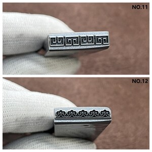 May include: Two metal stamps for leather crafting. The top stamp features a Greek key design. The bottom stamp features a wave design. The stamps are labeled NO.11 and NO.12.