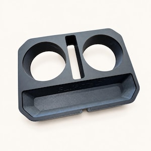 Op de afbeelding: Een matzwarte kunststof console-organizer met twee ronde bekerhouders, een centrale rechthoekige gleuf en een breder rechthoekig opbergvak aan de voorzijde. De tekst FLIP-T50 is in de voorrand van de tray gestanst.