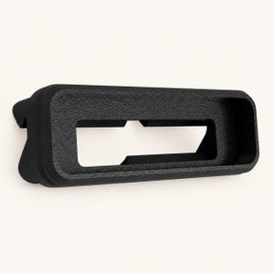 May include: A matte black rectangular frame with a textured surface and rounded corners. The object features a hollow center with a horizontal bar across the middle and angled support structures extending from the back side of the frame.