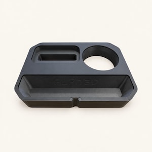 Op de afbeelding: Een matzwarte bureau-organizer met een rechthoekige gleuf, een ronde bekerhouder en een breed voorvak met de in reliëf aangebrachte tekst FLIPIT3D. De organizer heeft een trapeziumvorm met afgeronde hoeken en een kleine inkeping aan de voorzijde.