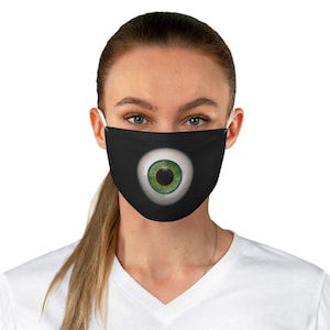 May include: A black face mask featuring a large green eye graphic. The eye is white with a green iris and a black pupil.
