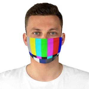 May include: A person wearing a face mask with a colorful television test pattern design. The mask is made of fabric and has a blue, gray, white, black, red, pink, green, turquoise, and yellow pattern.