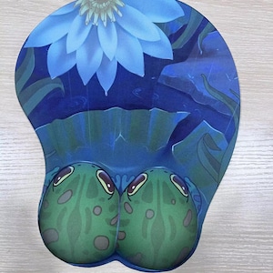 May include: Ergonomic mouse pad with a blue lotus flower design and two green frog-shaped wrist rests. The pad features a dark blue background with water and lily pads.