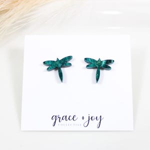 Op de afbeelding: Tealblauwe libellen oorbellen met een marmer effect. De oorbellen liggen op een witte kaart met de tekst "grace + joy collective".