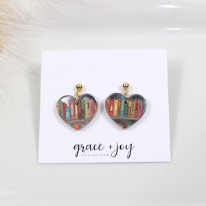 Peut inclure: Une paire de boucles d'oreilles en forme de c&oelig;ur avec une finition dor&eacute;e. Les boucles d'oreilles pr&eacute;sentent un design clair et transparent avec une image color&eacute;e d'une biblioth&egrave;que remplie de livres &agrave; l'int&eacute;rieur de chaque c&oelig;ur.