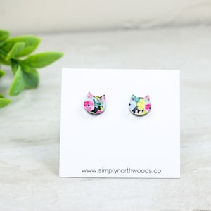 May include: A pair of floral cat stud earrings on a white card with the text "www.simplynorthwoods.co".