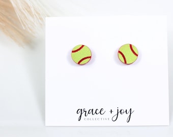 Peut inclure: Une paire de petites boucles d'oreilles rondes avec un motif de balle de softball jaune et rouge. Les boucles d'oreilles sont présentées sur une carte blanche avec le texte "grace + joy collective".