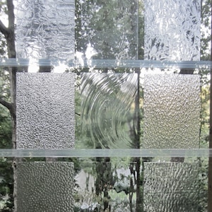 May include: Nine different types of textured glass panels, each with a unique pattern. The panels are arranged in a grid pattern, with three rows and three columns.
