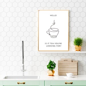 May include: A gold framed print with a black and white line drawing of a teacup with steam rising from it. The text "HELLO IS IT TEA YOU'RE LOOKING FOR?" is below the drawing.