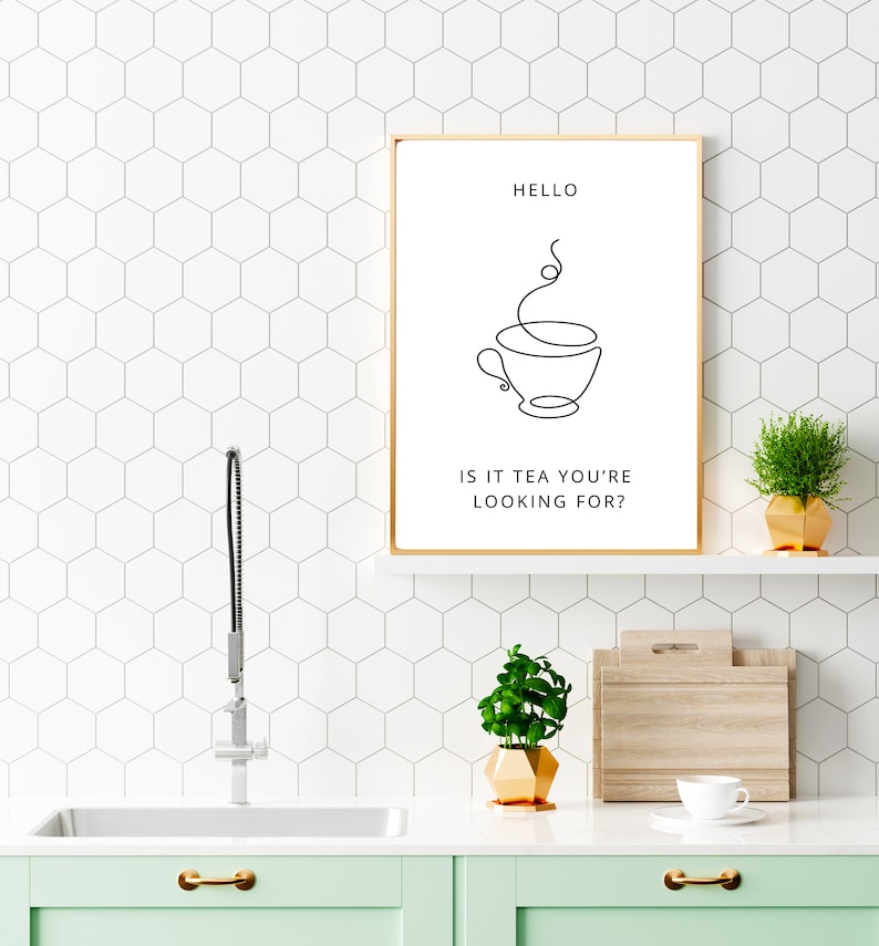 May include: A gold framed print with a black and white line drawing of a teacup with steam rising from it. The text "HELLO IS IT TEA YOU'RE LOOKING FOR?" is below the drawing.
