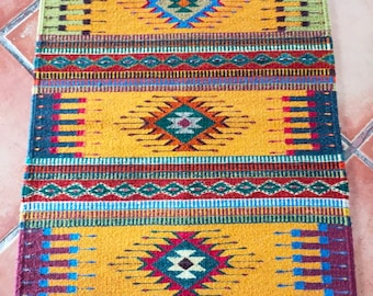 May include: A colorful woven rug with a geometric pattern in shades of red, yellow, blue, green, and black. The rug has a traditional Southwestern design.